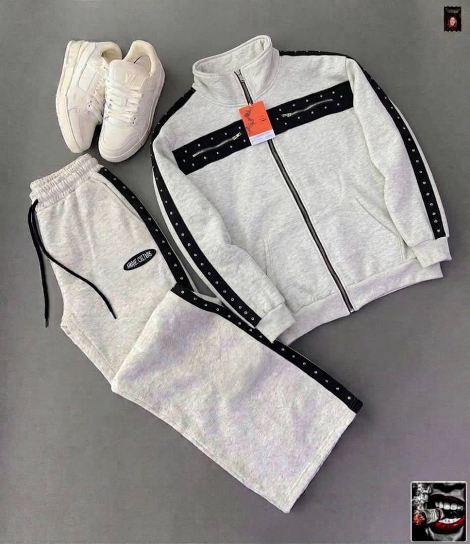 White tracksuit with black studded panels, zip details and Amour Culture logo, paired with white sneakers.