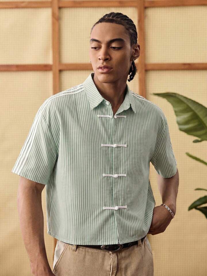 Front view of model wearing green striped short sleeve frog button shirt.