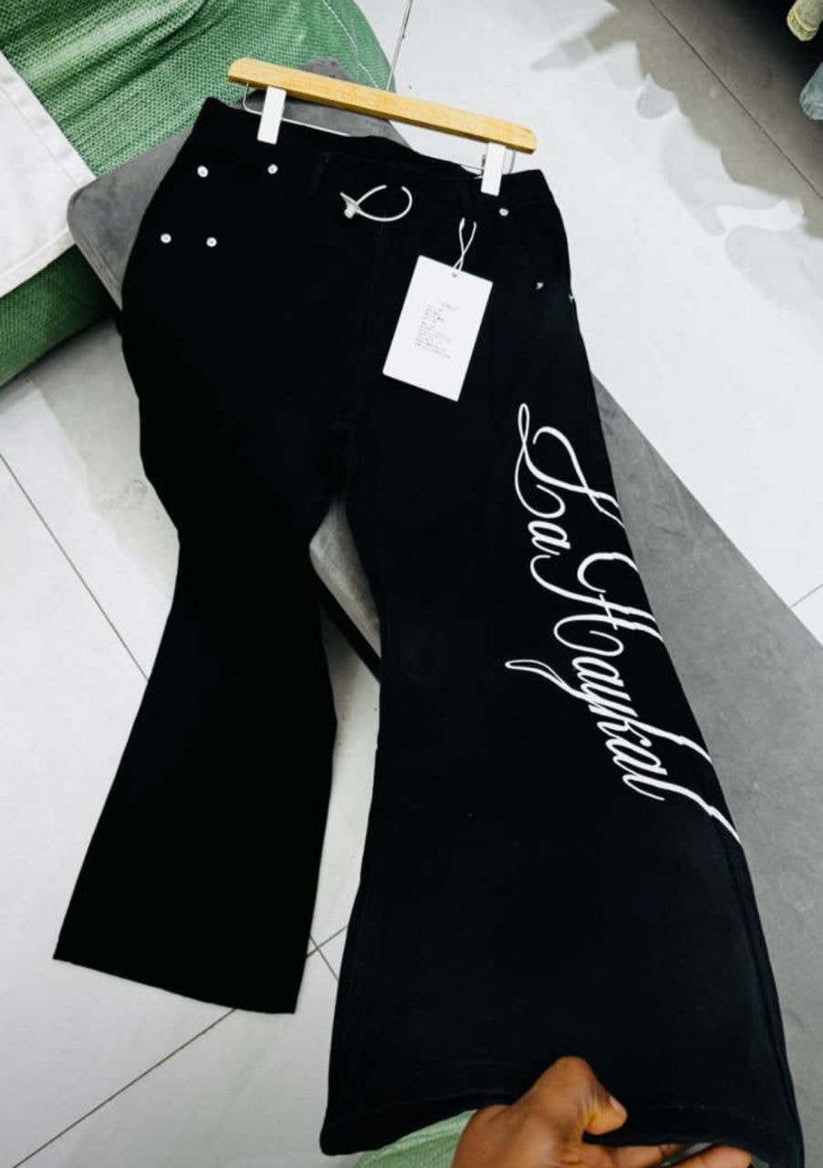 Black La Haykal jeans with white script held up for display.