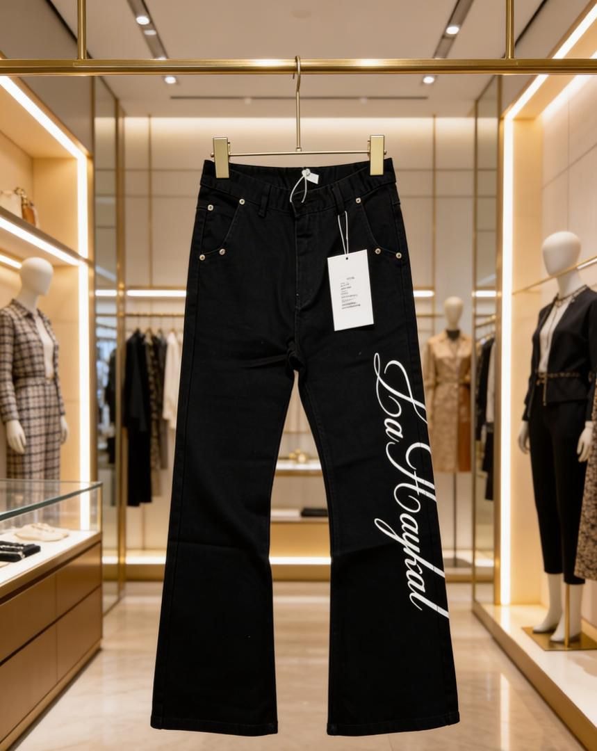 Black La Haykal jeans with white script hanging in a luxury retail store.