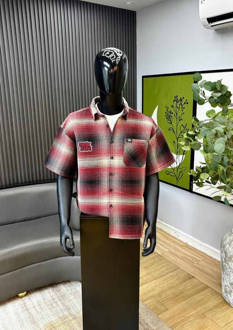 Mannequin wearing red plaid short sleeve button-down shirt with chest pocket.