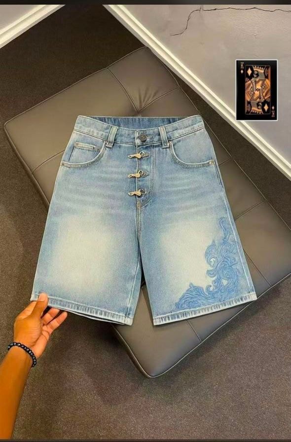 Light wash blue denim jorts with swirl embroidery on the right leg and multi-button fly closure.