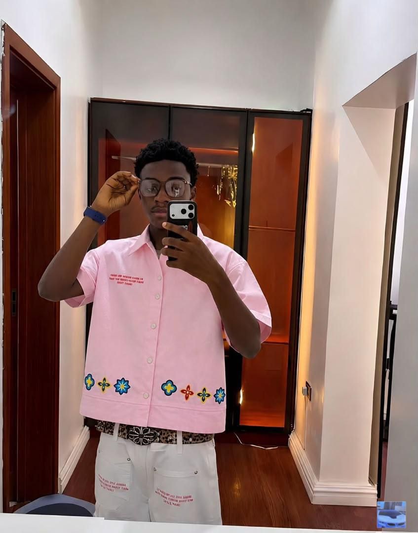 Man wearing pink short sleeve button-up shirt with floral embroidery along the hem and chest print.