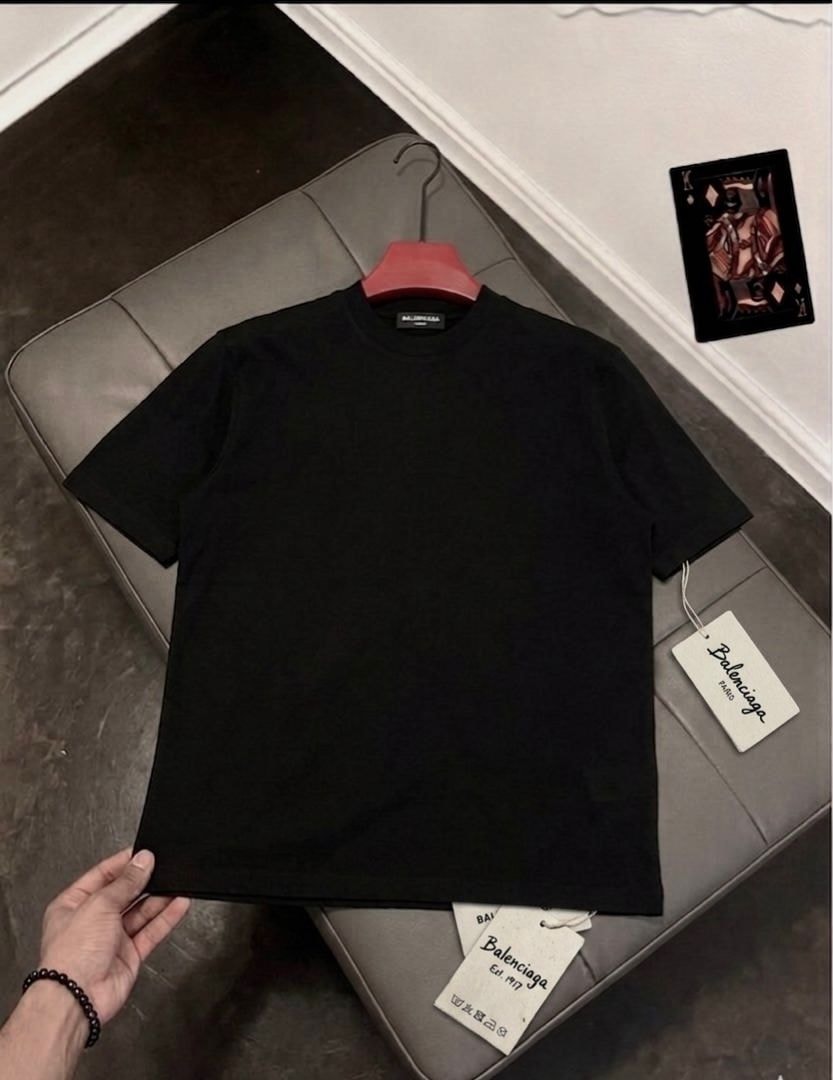 Black Balenciaga plain t-shirt on red hanger displayed on grey couch with tags.