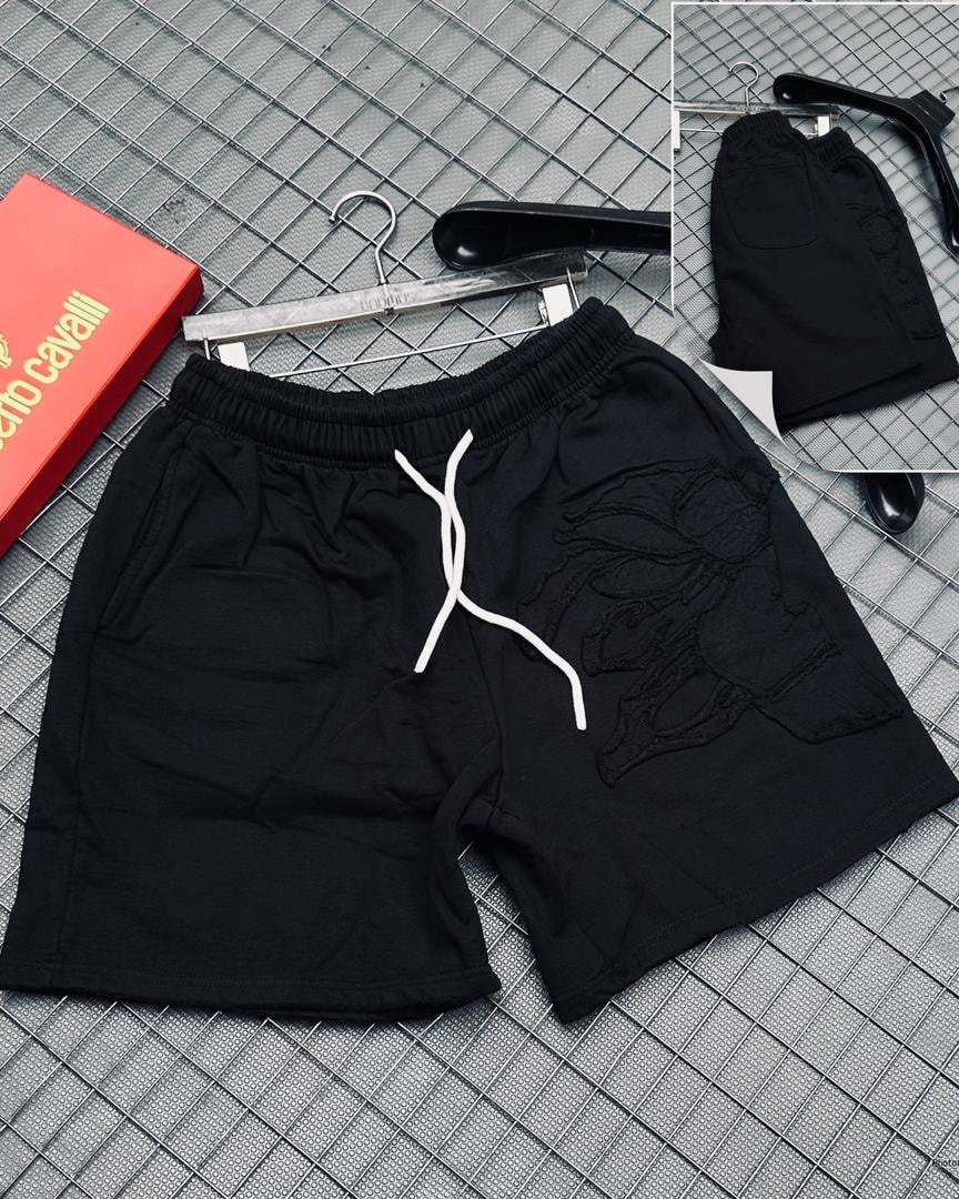 Black shorts featuring large peacock embroidery on the leg, white drawstring, on grid with hangers.