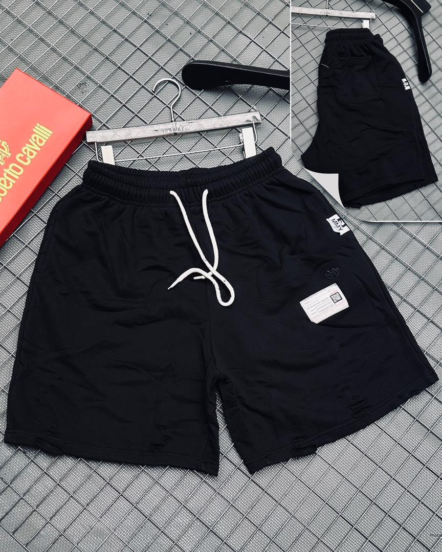 Black distressed shorts with white drawstring, logo patch, rips, and Roberto Cavalli box on grid background.