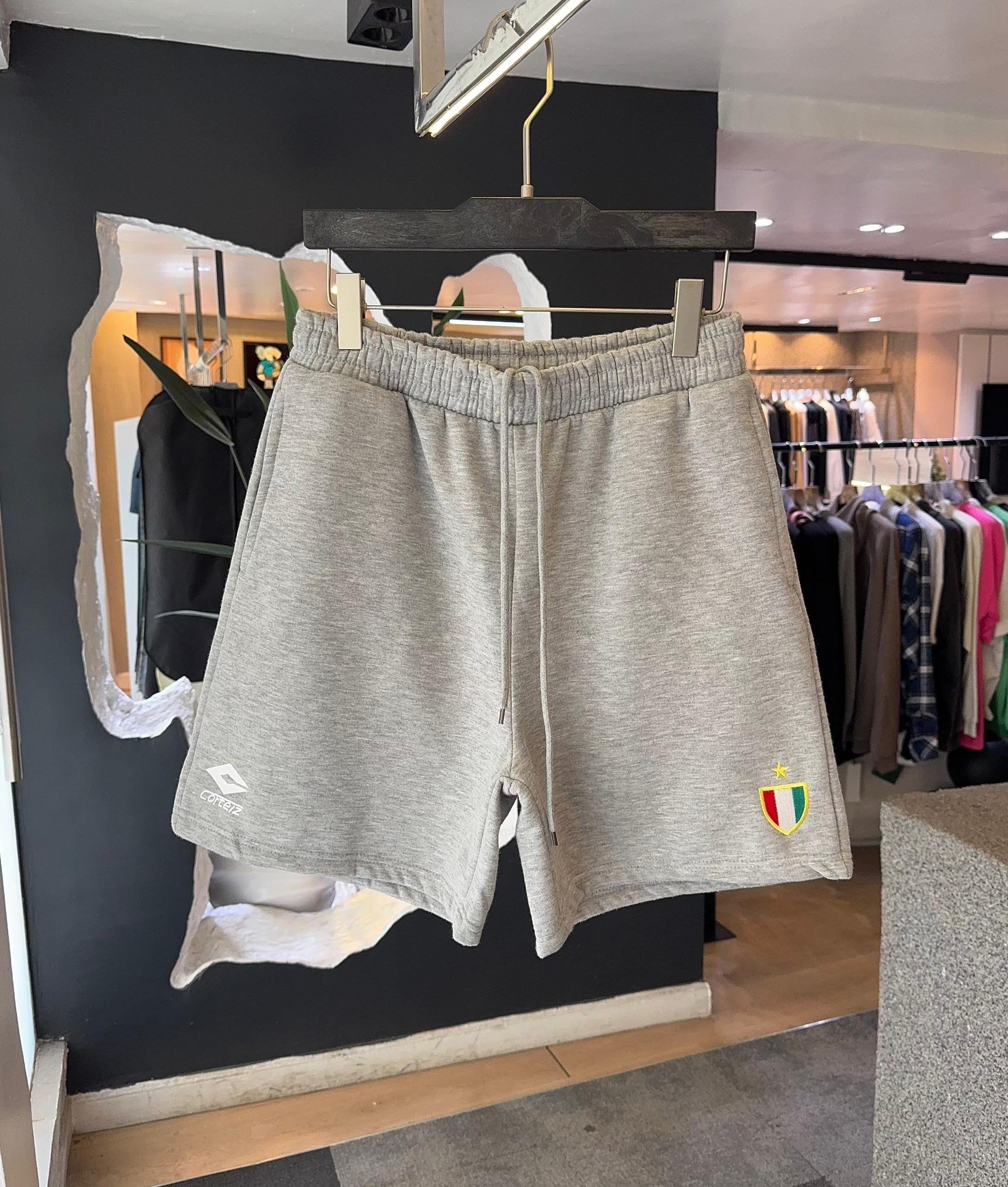 Gray Corteiz shorts with elastic waistband, drawstring and embroidered logos on both legs.