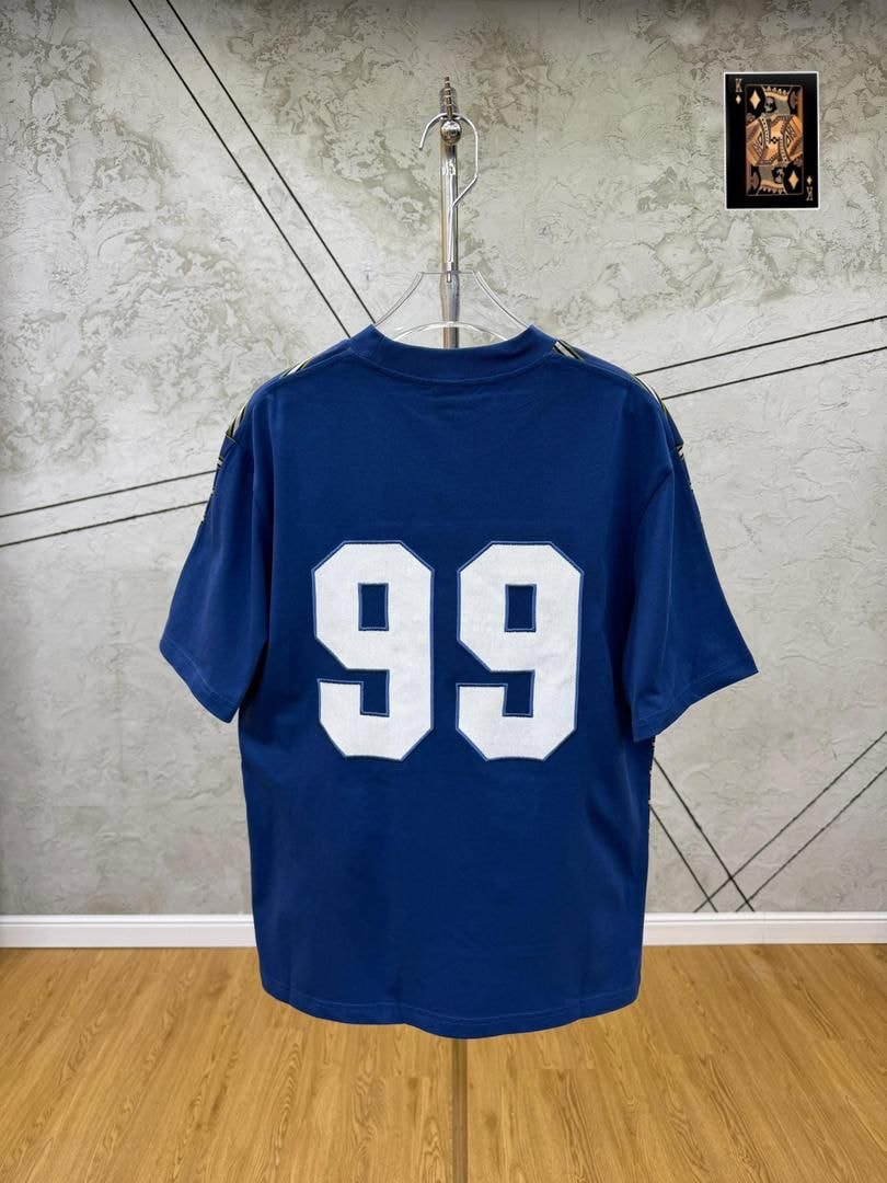 Blue 99 numbered t-shirt back view hanging on stand.