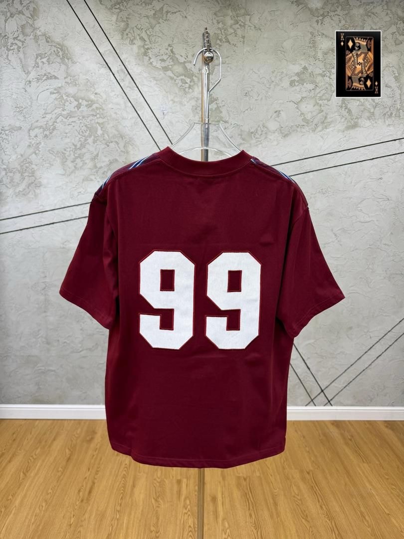 Maroon 99 numbered t-shirt back view hanging on stand.