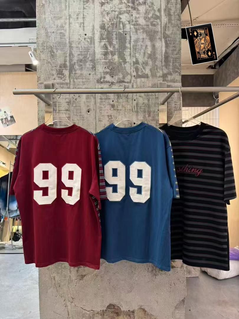 Backs of maroon 99, blue 99, and black striped t-shirts hanging together.