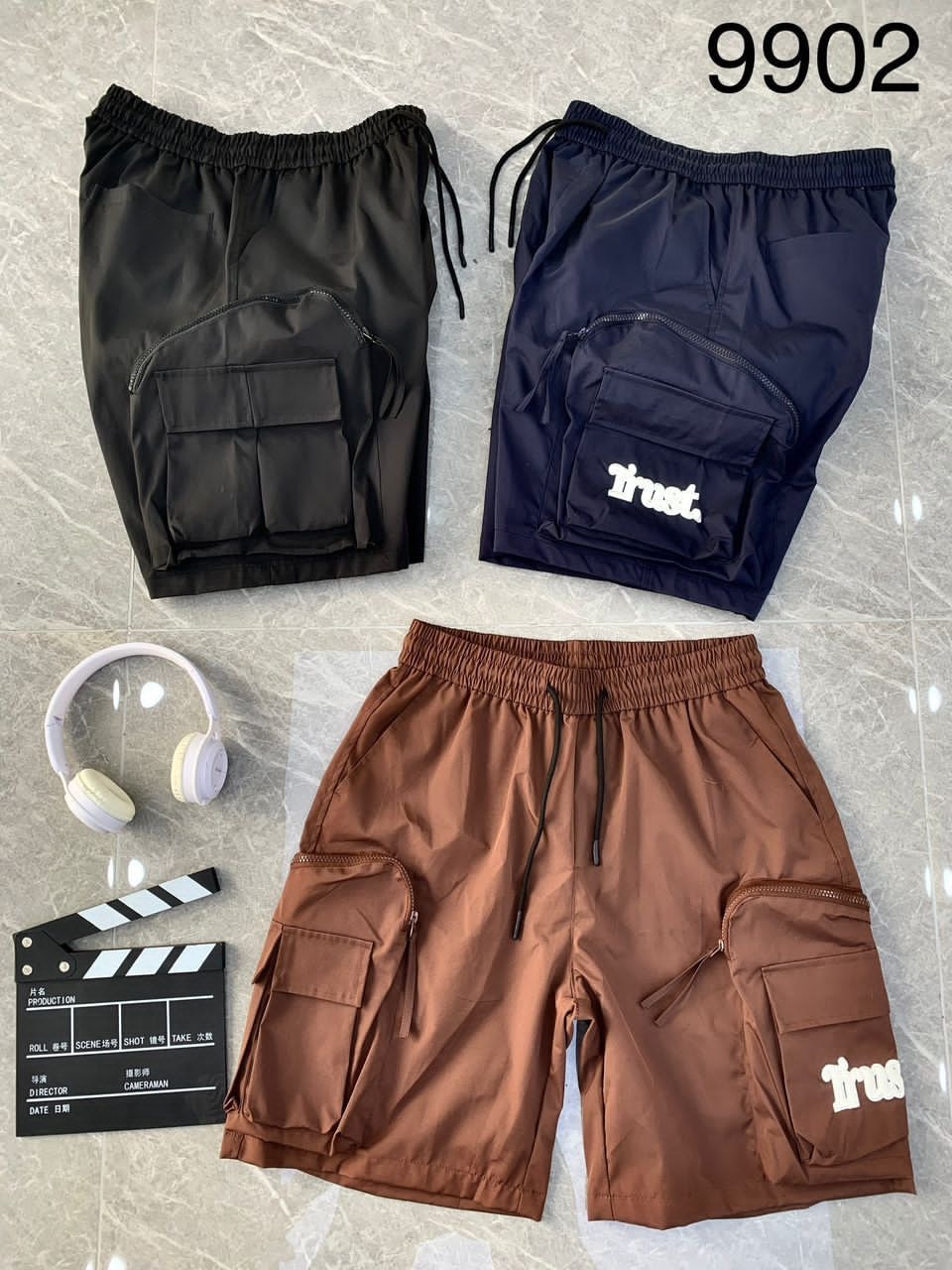 Black, navy, and brown combat cargo shorts with Trust graphic and accessories.