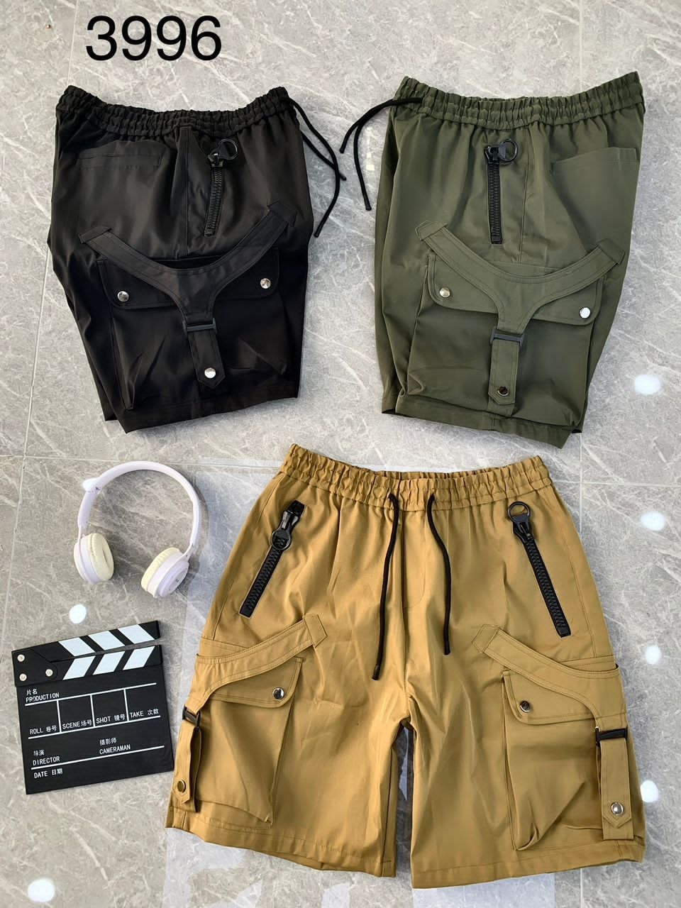 Black, olive, and tan combat cargo shorts with unique pocket details and props.