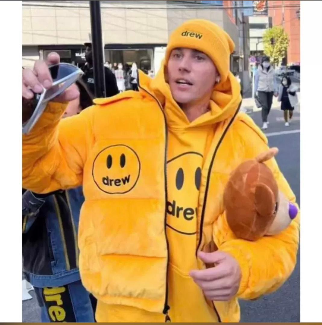 Man wearing yellow Drew puffer jacket and matching beanie on the street.