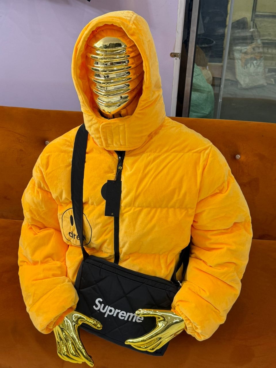 Yellow Drew puffer jacket displayed on a mannequin with accessories.