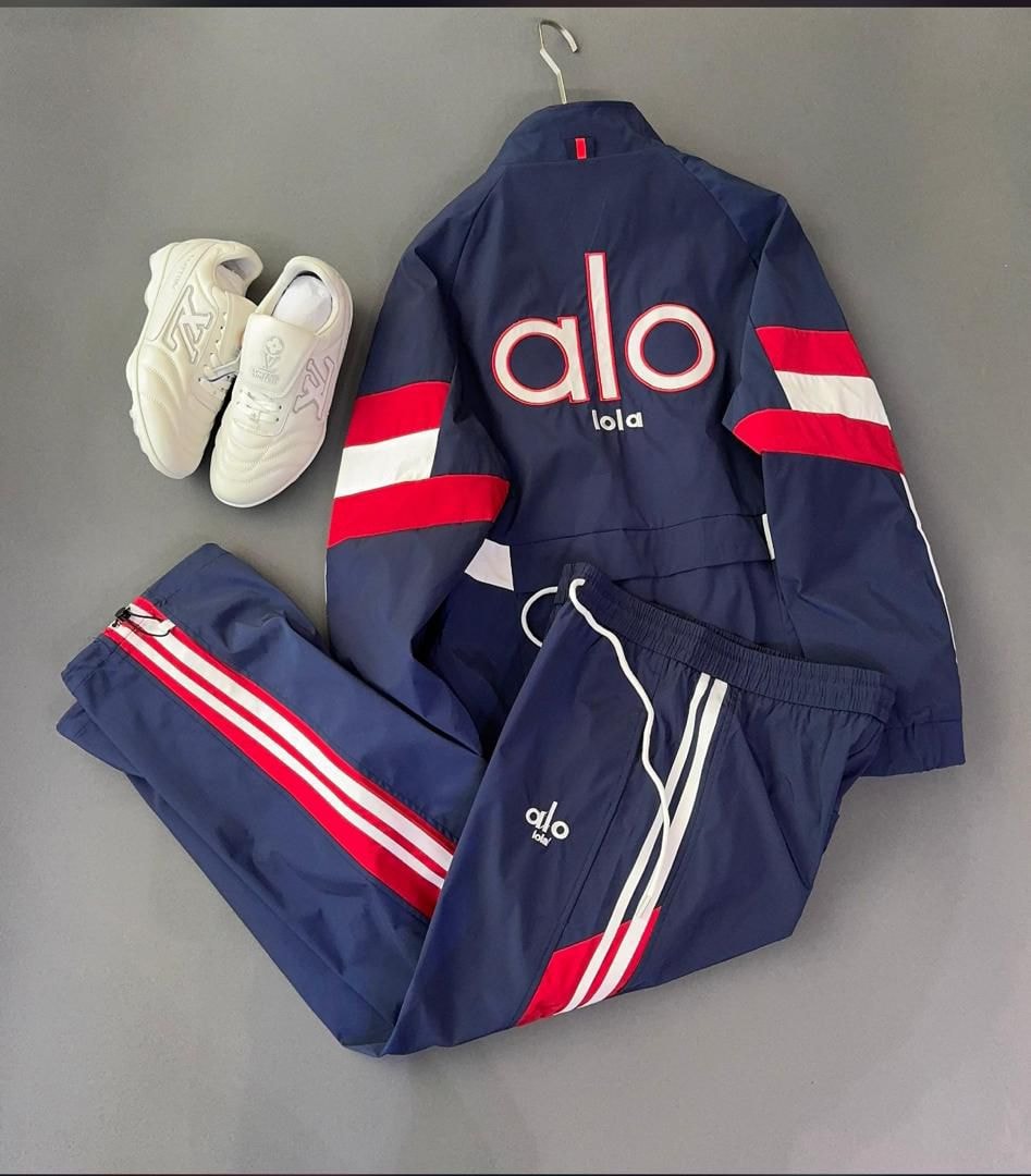 Navy Alo tracksuit set with red and white stripes displayed with white sneakers on gray background.