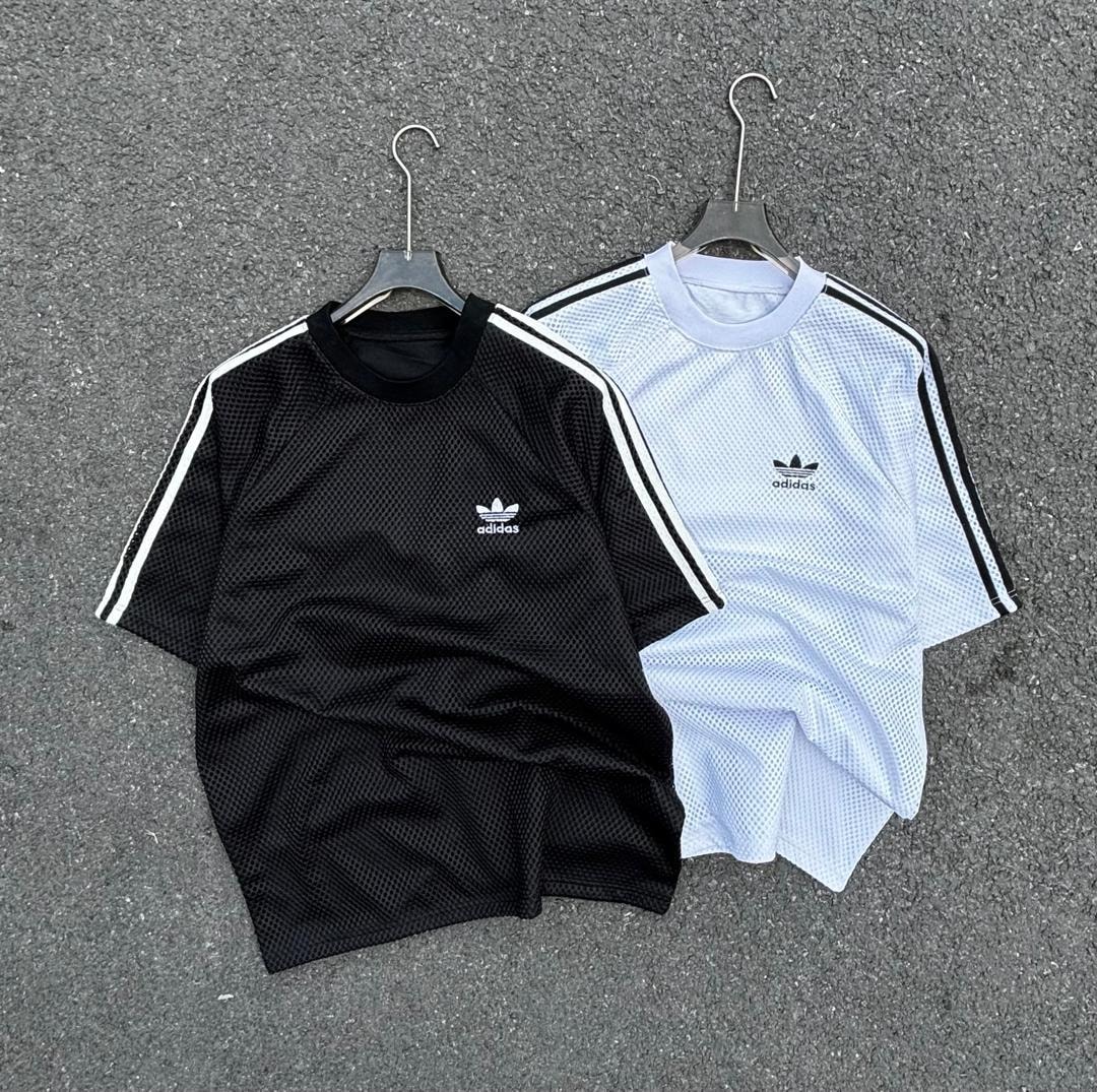 Black and white Adidas net mesh polo shirts with striped sleeves on pavement.