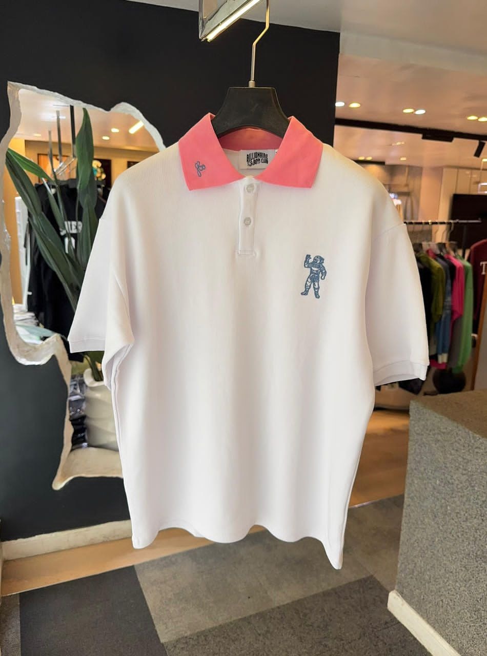 White Billionaire Boys Club polo with pink collar and blue astronaut embroidery on chest.