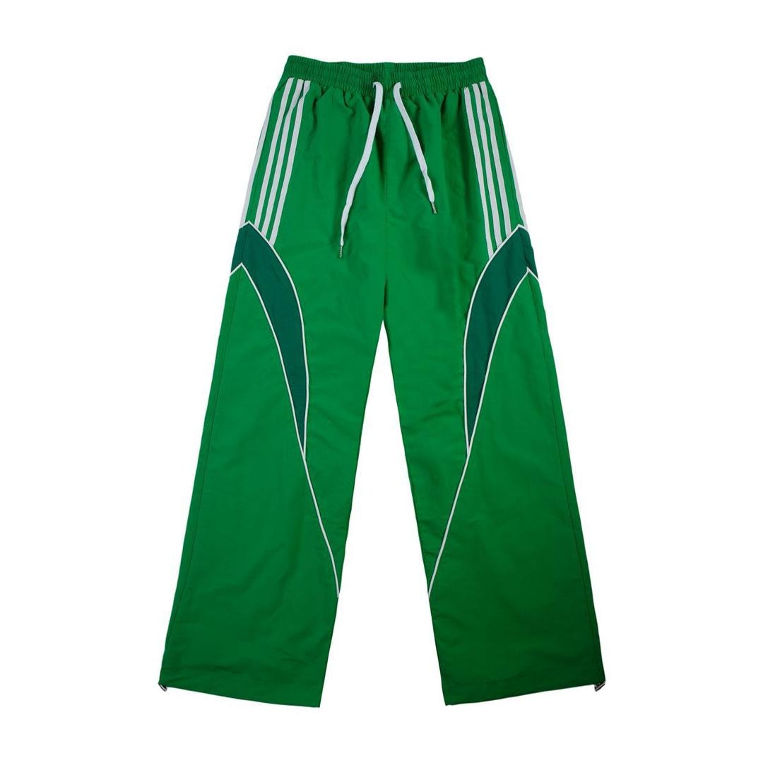 Green track pants with white side stripes and dark green curved panels.