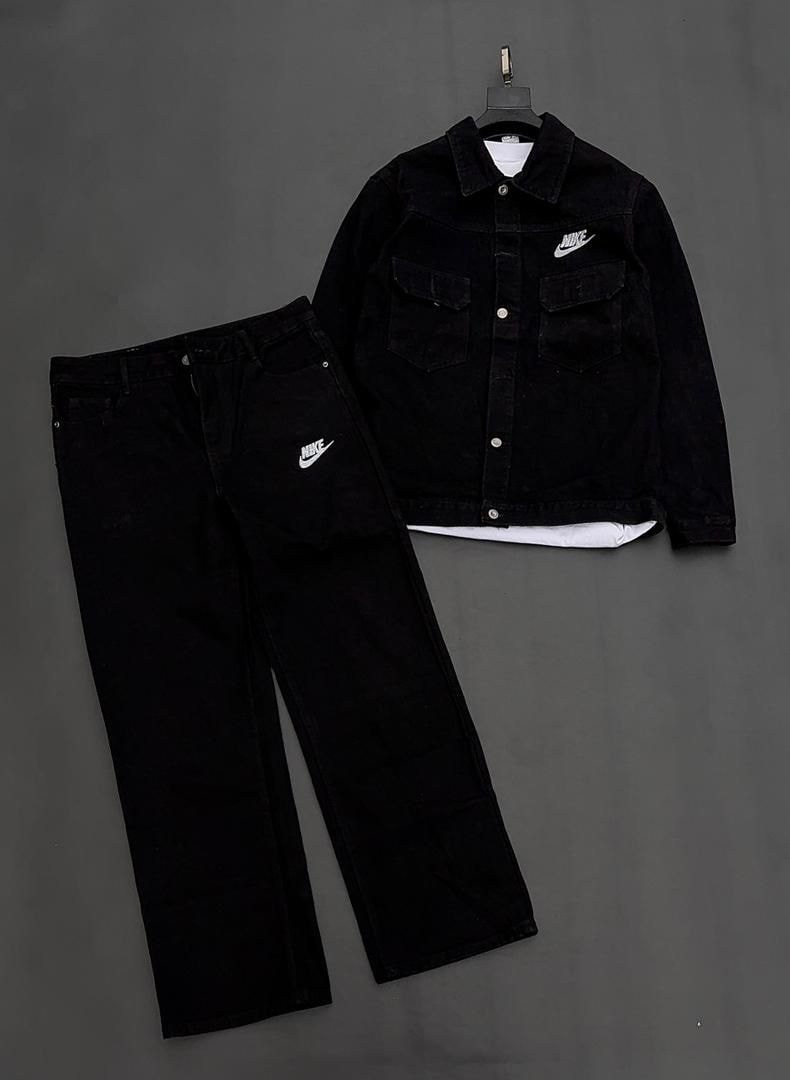 Flat lay view of black Nike denim jacket over a white tee with matching black jeans on gray background.