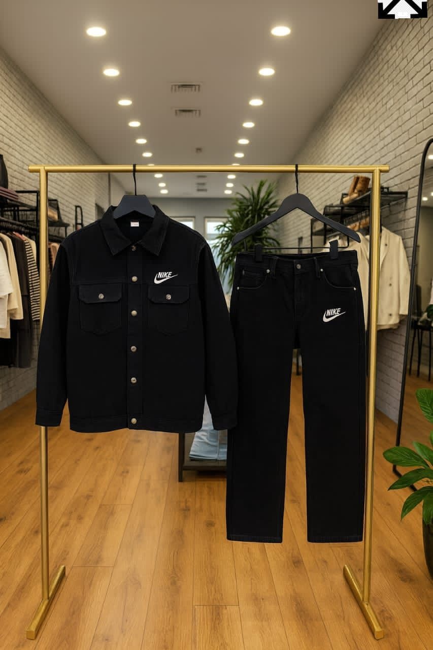 Black Nike denim jacket and jeans displayed on hangers in a retail store with wooden floors.