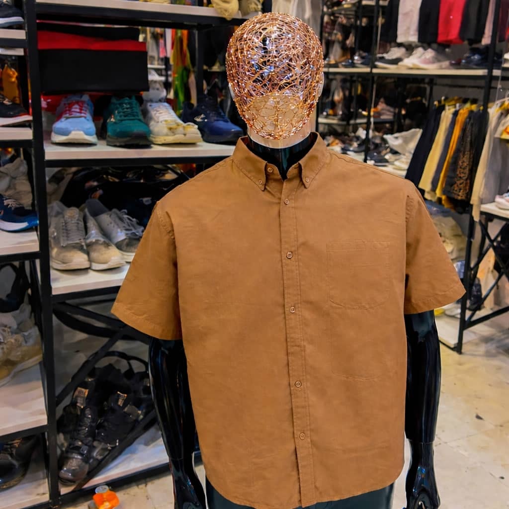 Brown short sleeve button-up shirt on mannequin in retail store.