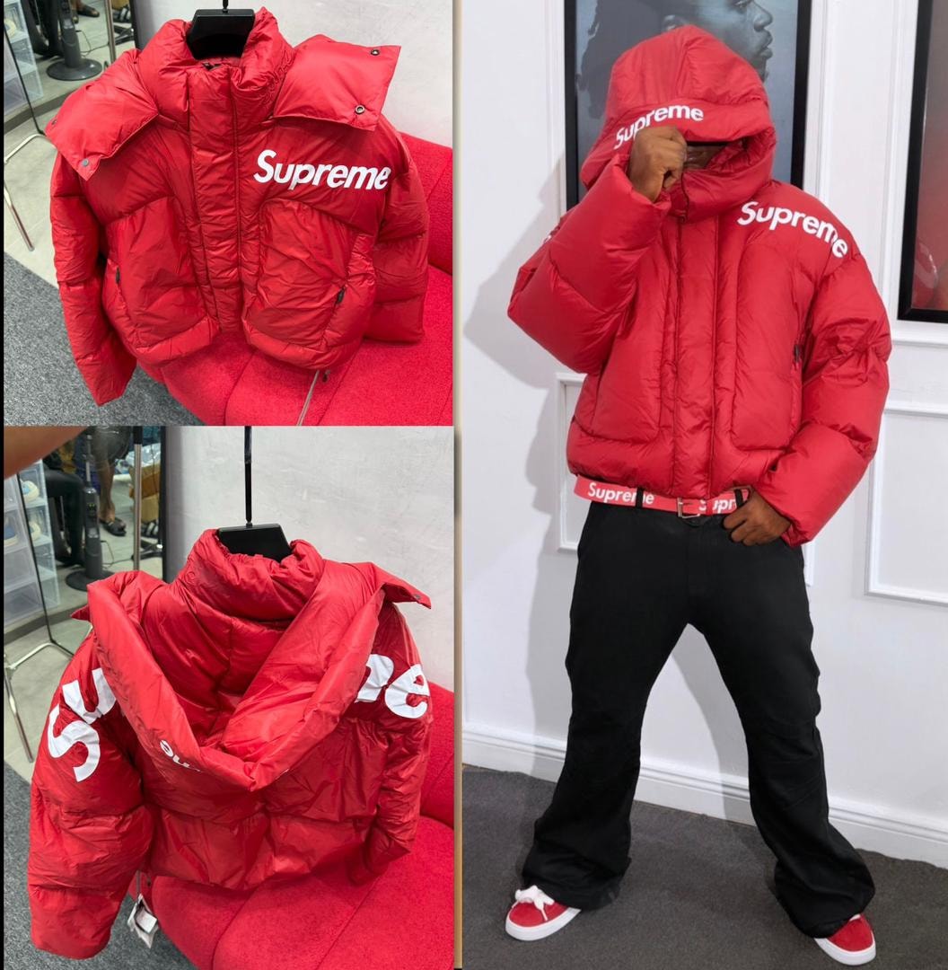 Supreme red puffer jacket displayed on red couch, close-up details, and worn by model with black pants.