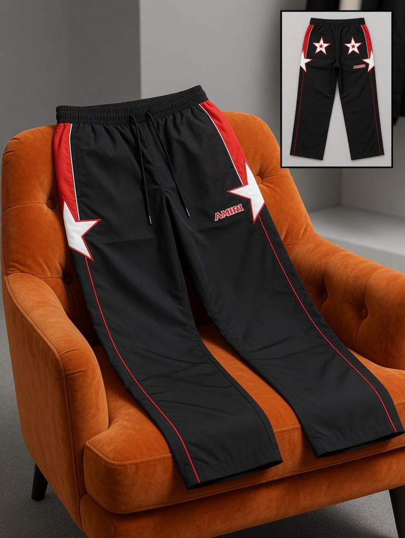 Black AMIRI star logo joggers on orange chair with inset back view.