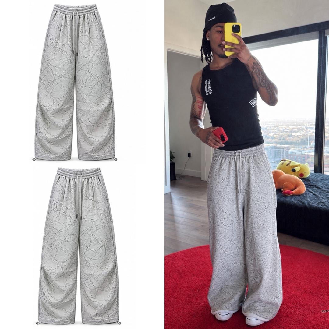 Model in black tank and beanie wearing gray marble-patterned wide-leg joggers.