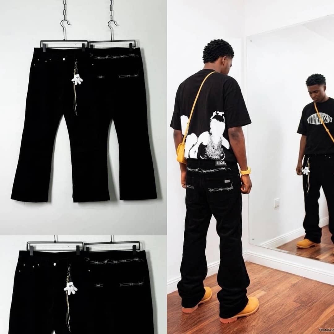 Man wearing black barbed wire embroidered jeans with glove keychain in mirror selfie.