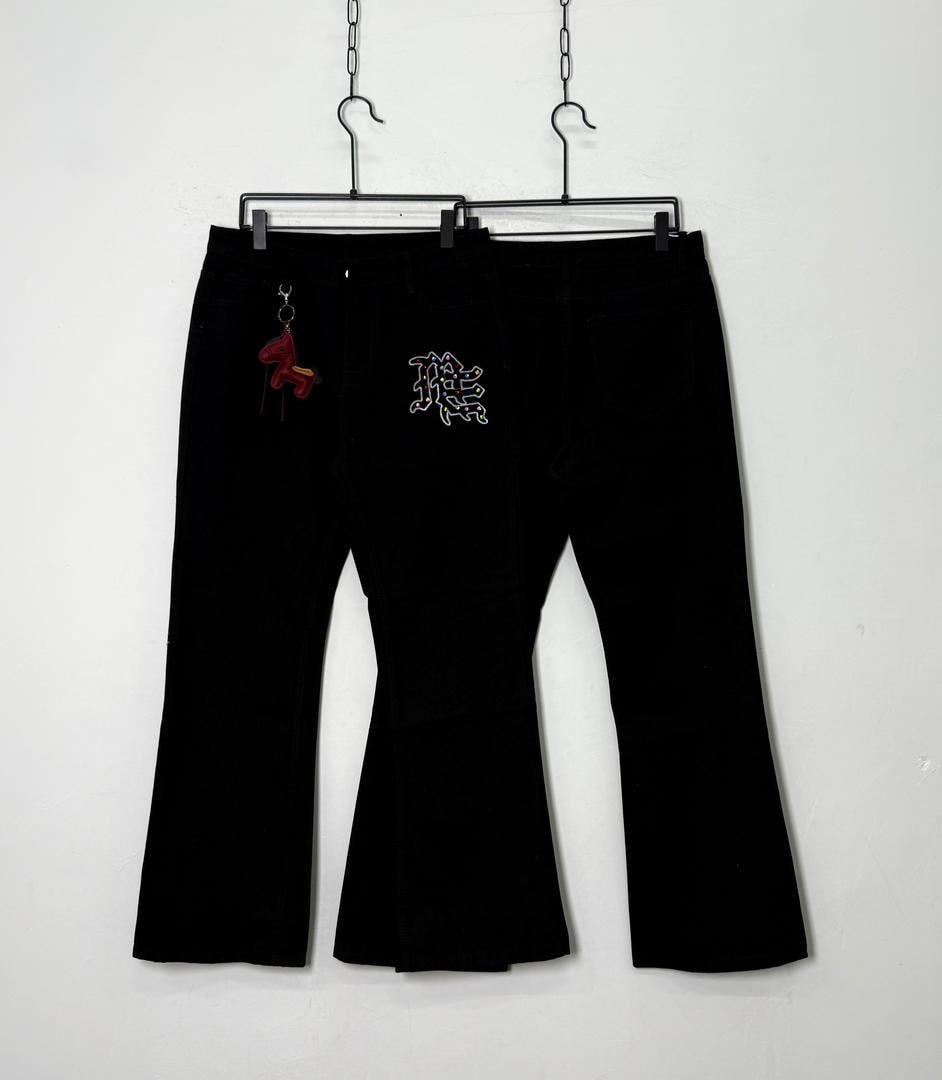 Black baggy flared jeans hanging side by side, one with red horse keychain and white embroidery.