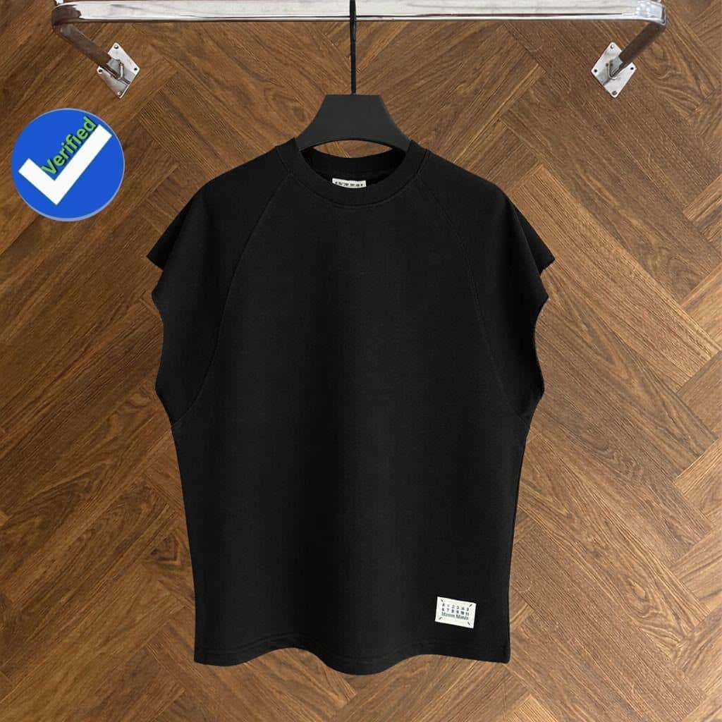 Black armless raglan top on black hanger against wooden floor.