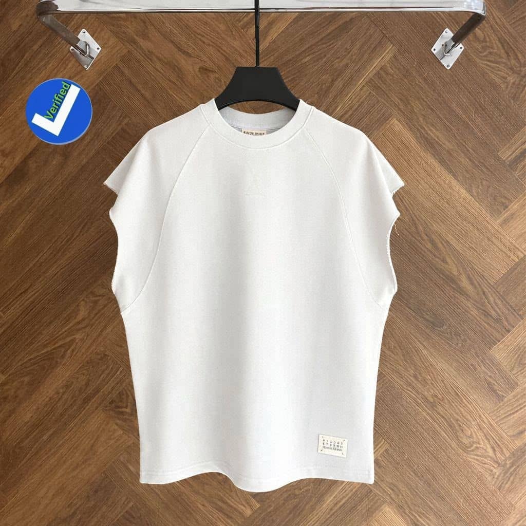 White armless raglan top on black hanger against wooden floor.