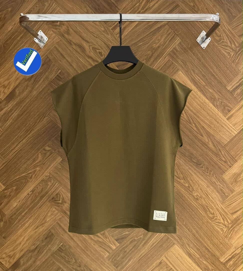 Olive green armless raglan top on black hanger against wooden floor.
