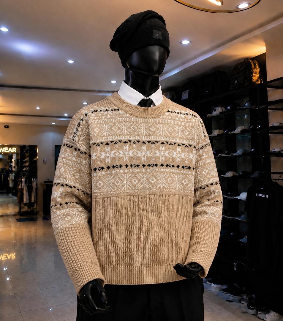 Mannequin wearing beige geometric patterned knit sweatshirt with black beanie and layered white shirt.