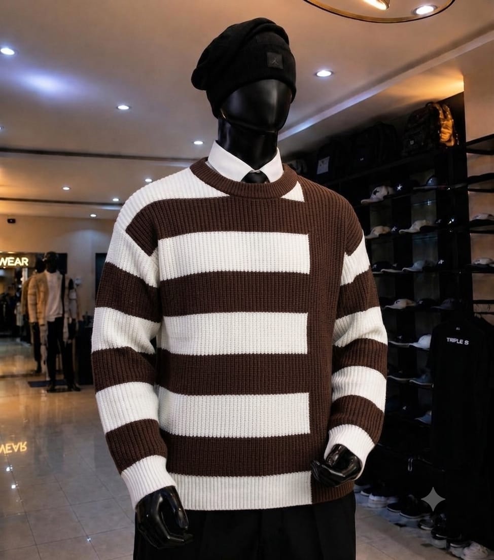 Mannequin wearing brown and white striped knit sweatshirt with black beanie, white shirt and black trousers.