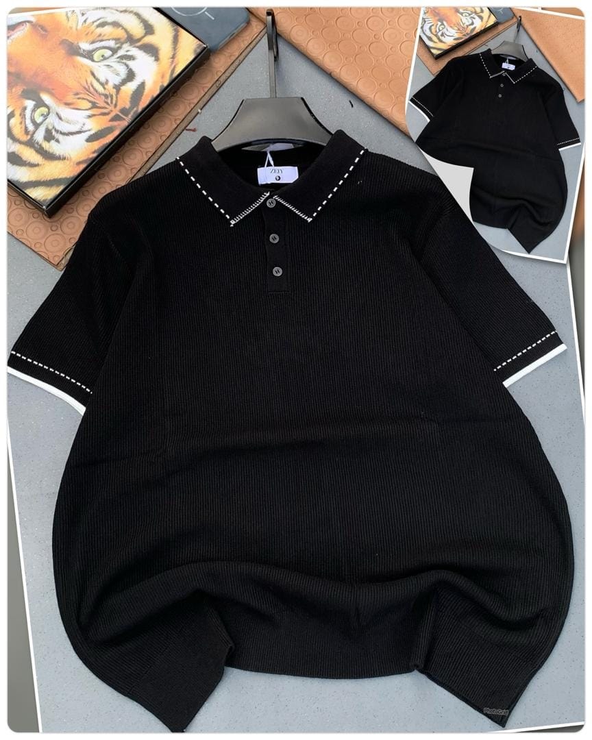 Black ribbed polo shirt with white contrast stitching on collar and cuffs, laid flat with inset view.