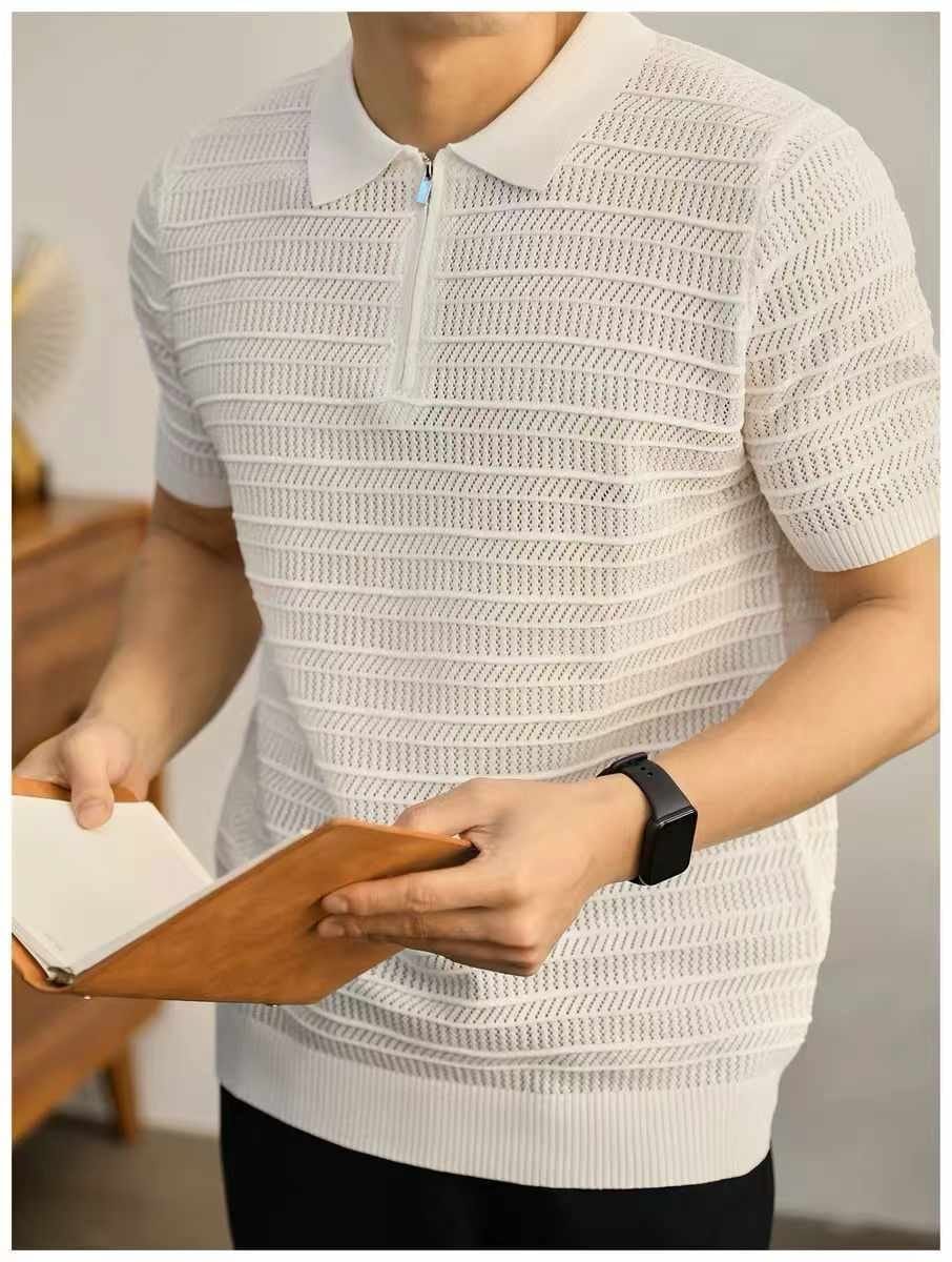 Man wearing white textured knitted zip polo shirt holding notebook.