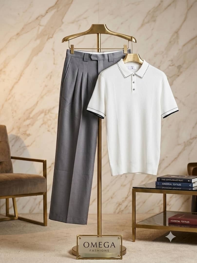 White polo with black trim and gray pleated pants on gold display stand with Omega sign.