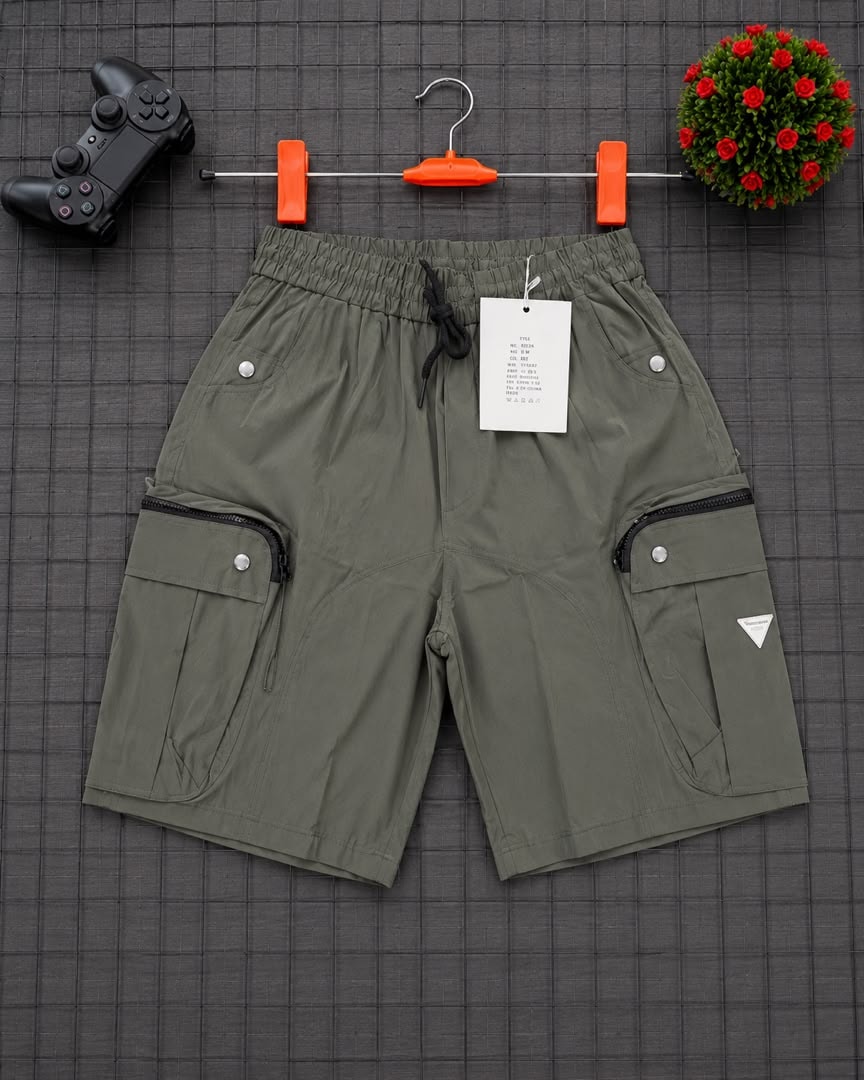 Olive cargo shorts with triangle logo on grid background.